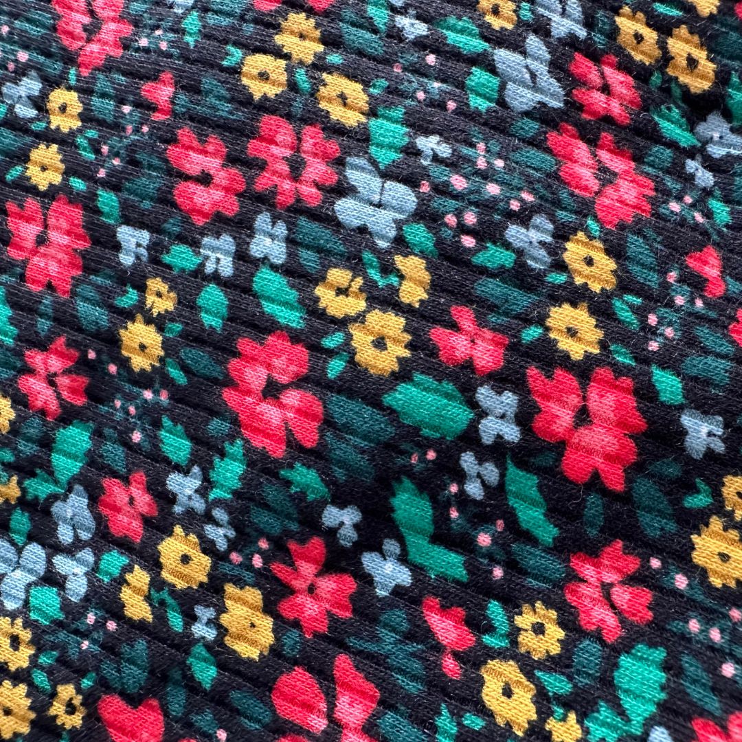 Black ribbed material midi length dress with red, yellow, and blue floral pattern.