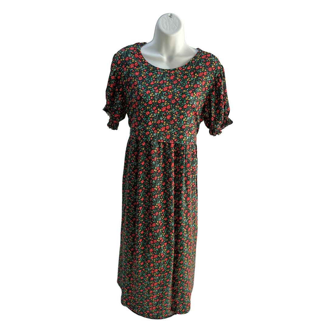 Black midi length dress with red, yellow, and blue floral pattern. Scoop neck, ribbed material, slight puffed short sleeve with scrunched band. Front flap for easy access for breastfeeding and pumping. Ties around the back to tighten as needed.