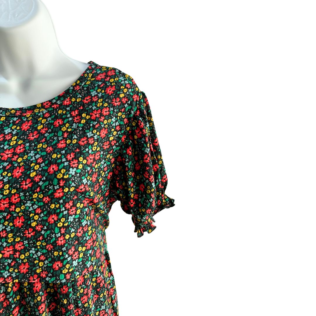 Black midi length dress with red, yellow, and blue floral pattern. Scoop neck, ribbed material, slight puffed short sleeve with scrunched band. Front flap for easy access for breastfeeding and pumping. Ties around the back to tighten as needed.