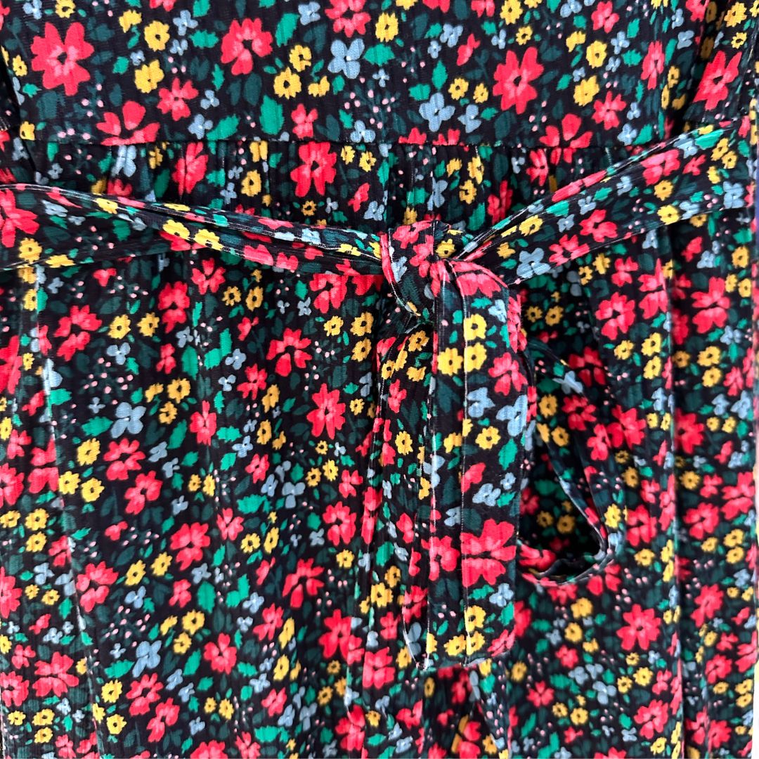 Black midi length dress with red, yellow, and blue floral pattern. Scoop neck, ribbed material, slight puffed short sleeve with scrunched band. Front flap for easy access for breastfeeding and pumping. Ties around the back show cased to show tighten as needed.