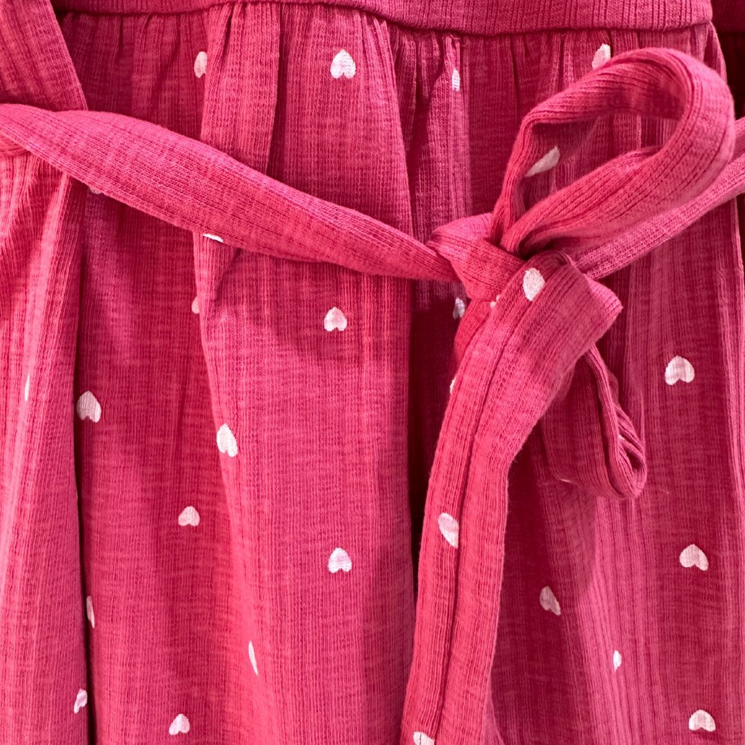 Pink with small white hearts, ribbed material, scoop neck, short sleeves, calf length dress. Front flap for easy breastfeeding and pumping. Tie around back show cased for tightening as needed.