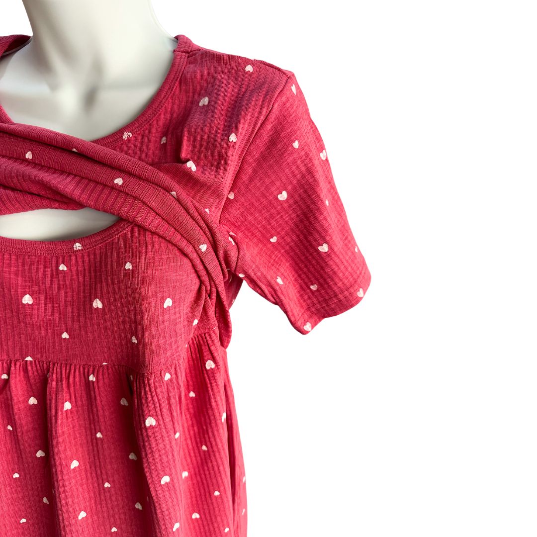 Pink with small white hearts, ribbed material, scoop neck, short sleeves, calf length dress. Front flap show cased open for easy breastfeeding and pumping. Tie around back for tightening as needed.